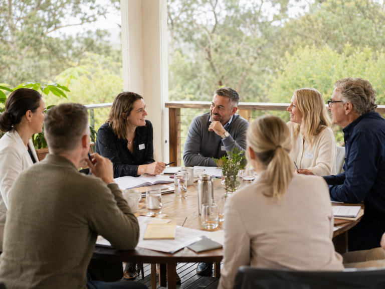 A group of professionals sitting around a table, engaged in a collaborative meeting on an outdoor deck