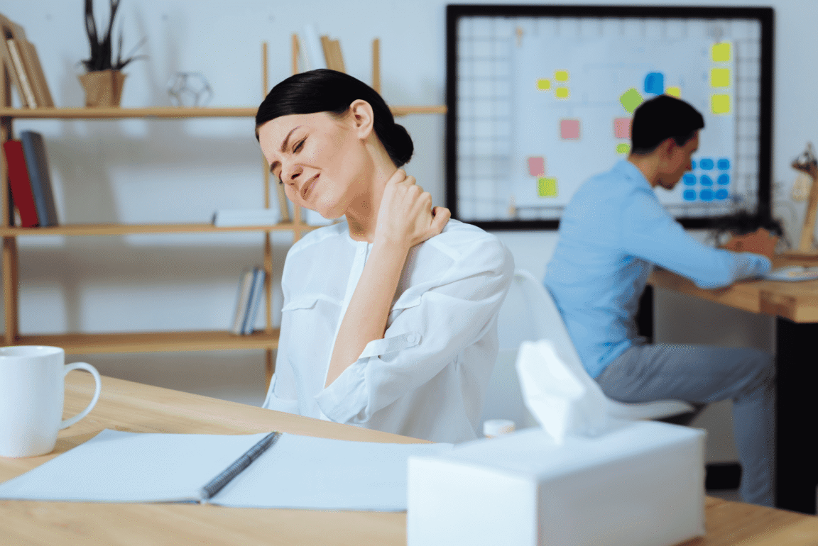 A person sitting at a desk with a hand on their neck